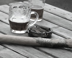 A glass tankard, a glass, and a stick on a bench